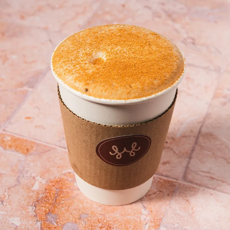 Capuchino con canela espolvoreada, vaso para llevar