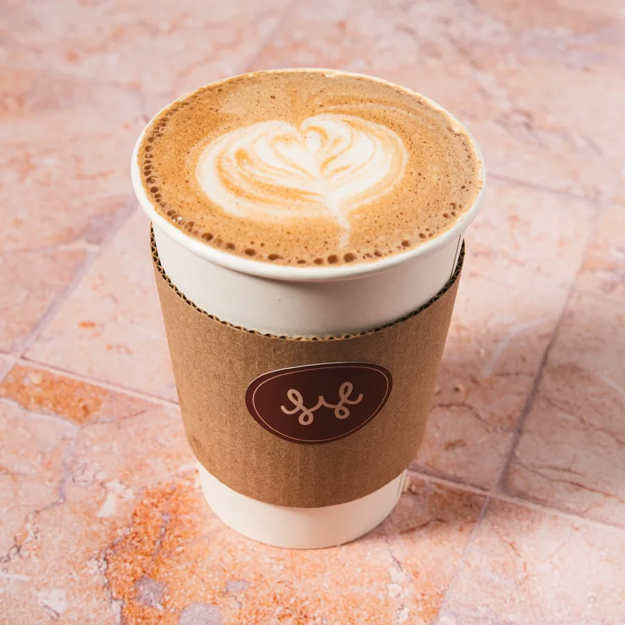 Latte caliente con arte en la espuma, vaso para llevar